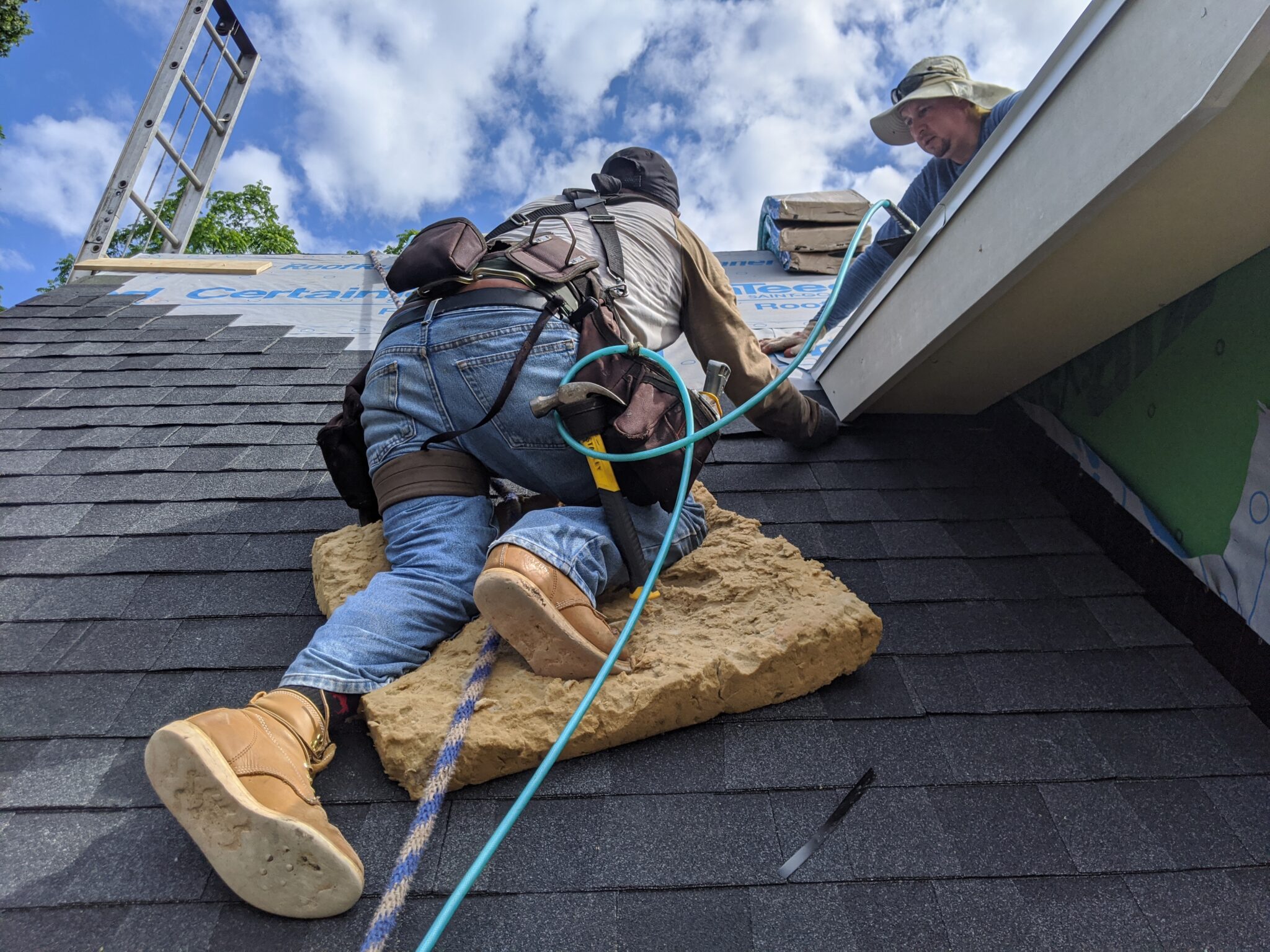Roofers repairing damaged asphalt shingles on a residential roof